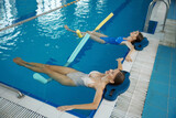 Fototapeta Tęcza - Two women doing relaxing exercise with noodles after training in swimming pool