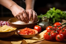 Persons Hand Garnishing A Bowl Of Salsa And Tortilla Chips