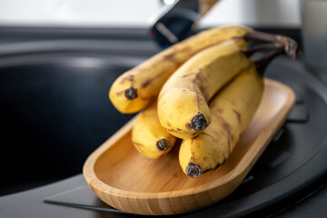 Sticker - A bunch of ripe yellow bananas in the kitchen near the sink.