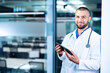 © Dmytro - Online medicine with handsome man GP doctor holding tablet computer in his hands looking at us with copy space