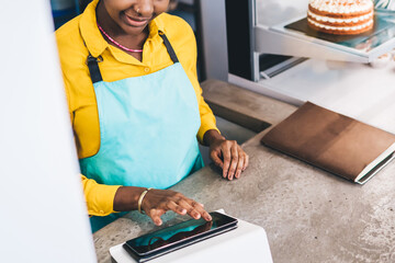 Wall Mural - Glad waitress watching tablet in pastry shop