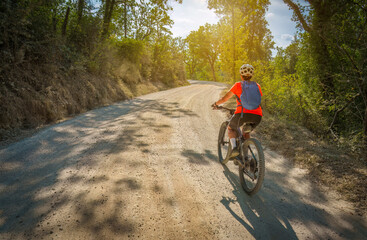 Wall Mural - nice senior woman riding her electric mountain bike on the famous white gravel road of Eroica near Gaiole in the Ghianti Area of Tuscany,Italy
