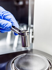 Wall Mural - A operator's hand is holding steel calibration weight to place on the analytical balance. Concept of quality control in a laboratory.