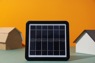 Solar panel and wooden houses on orange background