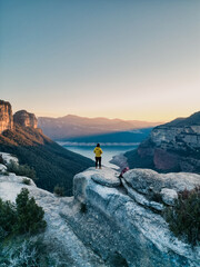 Persona en la alto de un acantilado disfrutando de un atardecer con vistas a un pantano