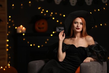 Wall Mural - Young woman in scary witch costume against blurred lights indoors, space for text. Halloween celebration