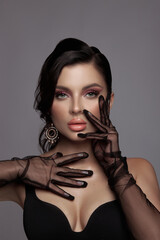 Wall Mural - Beauty portrait of a luxurious woman with pink makeup, clean skin, black gloves, veil on her hands, evening look