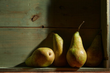 Image of Still Life with a stack of green Pears. Rustic wood background, antique wooden table