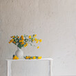 yellow chrysanthemums in white vase on background old white wall