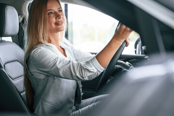 Side view. Woman is sitting in a car and driving it