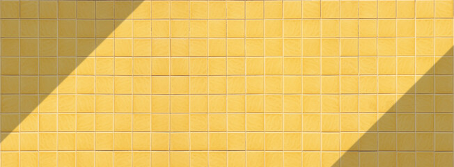 Yellow square tile wall background with sunlight and shadow on surface in panoramic view