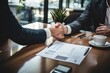 © Oulaphone - Estate agent male shaking hands with customer after contract signature at modern office with Mini house model with paper and pen on table.
