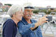 senior couple with camera taking selfie in a port