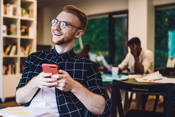 Wall Mural - Cheerful freelancer using smartphone in modern workspace