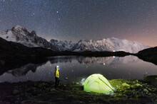 Person Admiring The Starry Sky Outside Tent Pitched On The Shore Of Cheserys Lake Surrounded By Alpine Landscape Of Mont Blanc, Chamonix, Haute Savoie, French Alps, France
