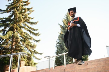 Poster - Portrait of indian handsome male graduate in graduation robe.