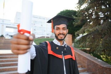 Poster - education, graduation and people concept - happy Indian Male graduate student.