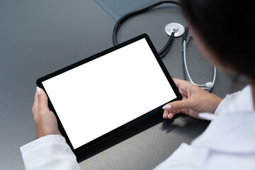 Doctor looking at blank mockup tablet computer with white screen for copy space. Background for medical product presentation or online medicine scene.