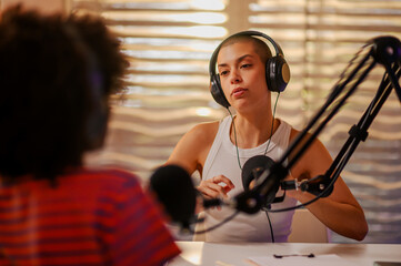 Wall Mural - A serious podcast guest is sitting with a host in a small recording studio