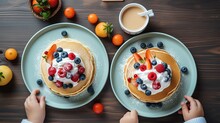 On A Blue Plate On A White Table, Kids' Hands Are Enjoying Pancakes Served As Rockets While Top View Flat Lay Is Present.