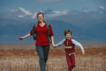 Canvas Print - Happy mother and son running on mountains background at autumn