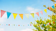 string of colorful pennant against blue sky in the garden as a summer party decoration