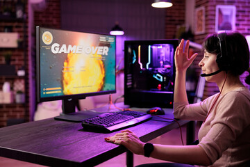 Wall Mural - Frustrated gamer losing singleplayer spaceship arcade racing videogame, seeing game over screen on gaming computer display. Woman being dissapointed after being defeated on difficult game level