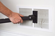 Person's hand vacuuming dirty return air vents