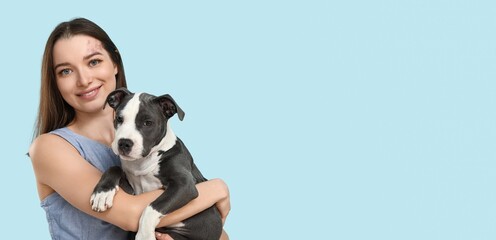 Wall Mural - Young girl holding cute puppy on light blue background with space for text