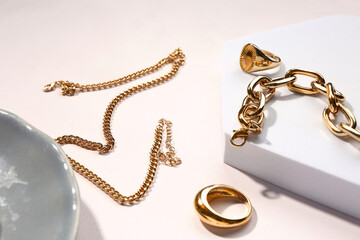 Plate and decorative podium with golden jewellery on white background