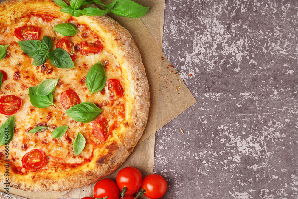 Baking paper with tasty pizza Margarita and basil on dark table
