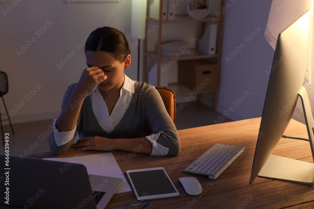 Tired young female programmer working in office at night
