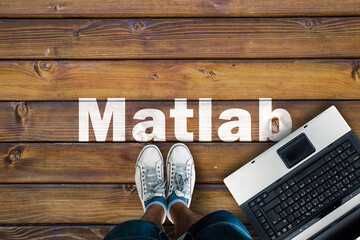 Wall Mural - legs in sneakers standing next to laptop and matlab on wooden floor. matlab programming language.