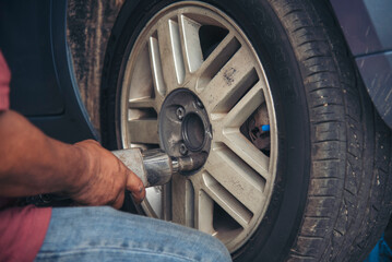 Close up Mechanic man hands repairing car auto repair shop uses jack change tyre. Man hands fixing Shock absorber machinery vehicle mechanical service. Vehicle Car overhaul maintenance engineer