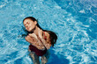 © SHOTPRIME STUDIO - Happy woman swimming in the pool in red swimsuit with loose long hair in the sunshine, skin protection with sunscreen, concept of relaxing on vacation.