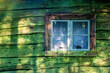 Window of an old wooden croft with green lichen on the wall