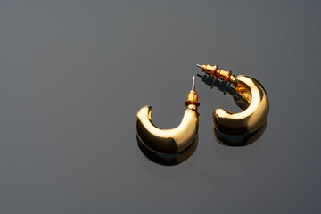 Wall Mural - Golden earrings on black background with reflection