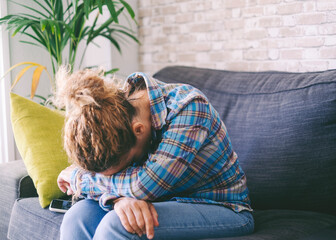 Wall Mural - Portrait of sad upset adult woman female sitting on sofa embrace knees lost in bad pessimistic thoughts suffer alone. Stressed adult people feel lonely desperate has broken heart. Female life problems