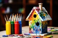 Homemade Birdhouse With Paints And Brushes On Wooden Table