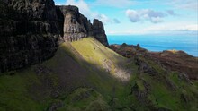 Light Bursts Between Cliffs In The Scottish Highlands Illuminating Grassy Patch Below Exposed Rock