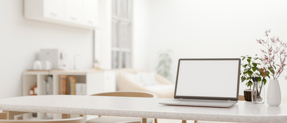 a white-screen laptop mockup on a dining table in a modern white living room. close-up image