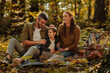 © bernardbodo - Mother, father and their little daughter sitting on a blanket, holding apples and smiling in forest