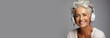 Beautiful elderly happy woman with headphones on gray background. Banner. Copy space for text