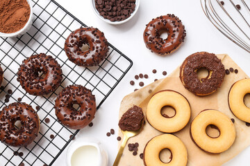 Wall Mural - Chocolate donuts, spoon, whisk and bowls on white background, top view