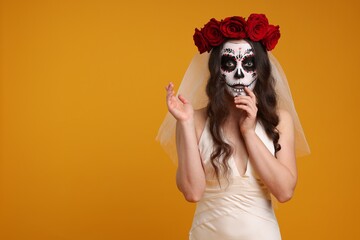 Wall Mural - Young woman in scary bride costume with sugar skull makeup and flower crown on orange background, space for text. Halloween celebration