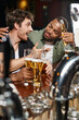 © LIGHTFIELD STUDIOS - african american man hugging excited friend chatting and holding beer in bar, male friendship