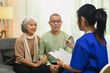 © Prathankarnpap - Smiling senior couple listening attentively to nurse or general practitioner explaining therapy details during home visit