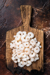 Wall Mural - Raw fresh Peeled Shrimps, Prawns set on wooden board.  Dark background. top view