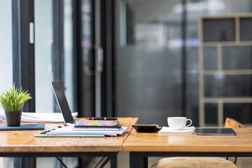 Wall Mural - Laptop Computer, notebook, and eyeglasses sitting on a desk in a large open plan office space after working hours	