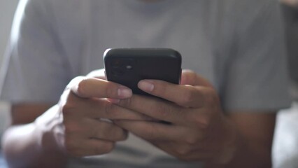 Hands of Asian man holding checking touching scrolling smartphone from bed room
